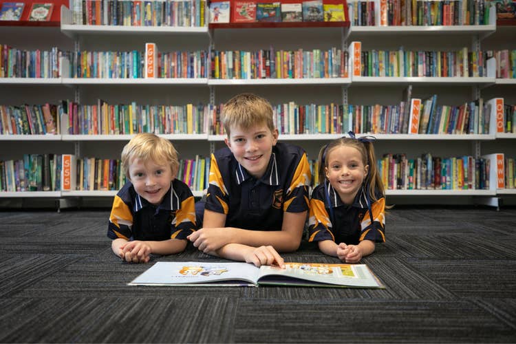3 Students in library reading a book