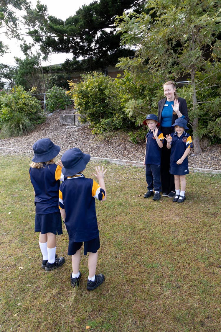 Students waving to teacher in playground